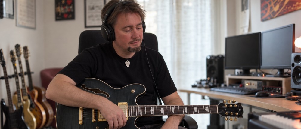 Max Gotta nel suo studio con le cuffie, mentre ascolta con una chitarra semiacustica in grembo