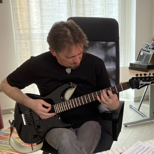 Max Gotta suona una chitarra elettrica nera nel suo studio, davanti alla postazione di registrazione
