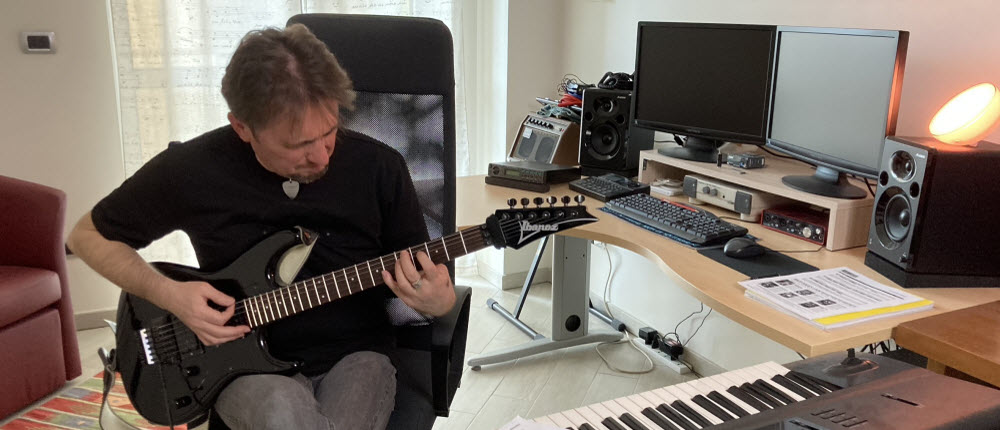 Max Gotta suona una chitarra elettrica nera nel suo studio, davanti alla postazione di registrazione