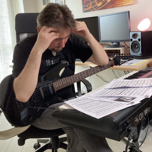 Max Gotta con le mani tra i capelli davanti agli spartiti, la chitarra elettrica in grembo, nel suo studio