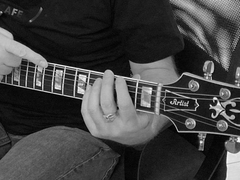 Primo piano delle mani di Max Gotta sul manico della chitarra